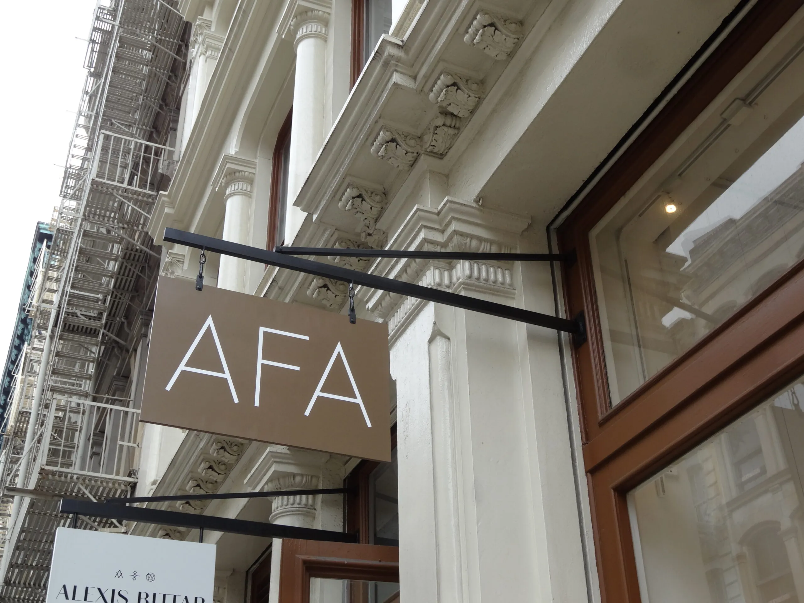 Projecting blade sign with a dimensional logo mounted on a building's stone frontage