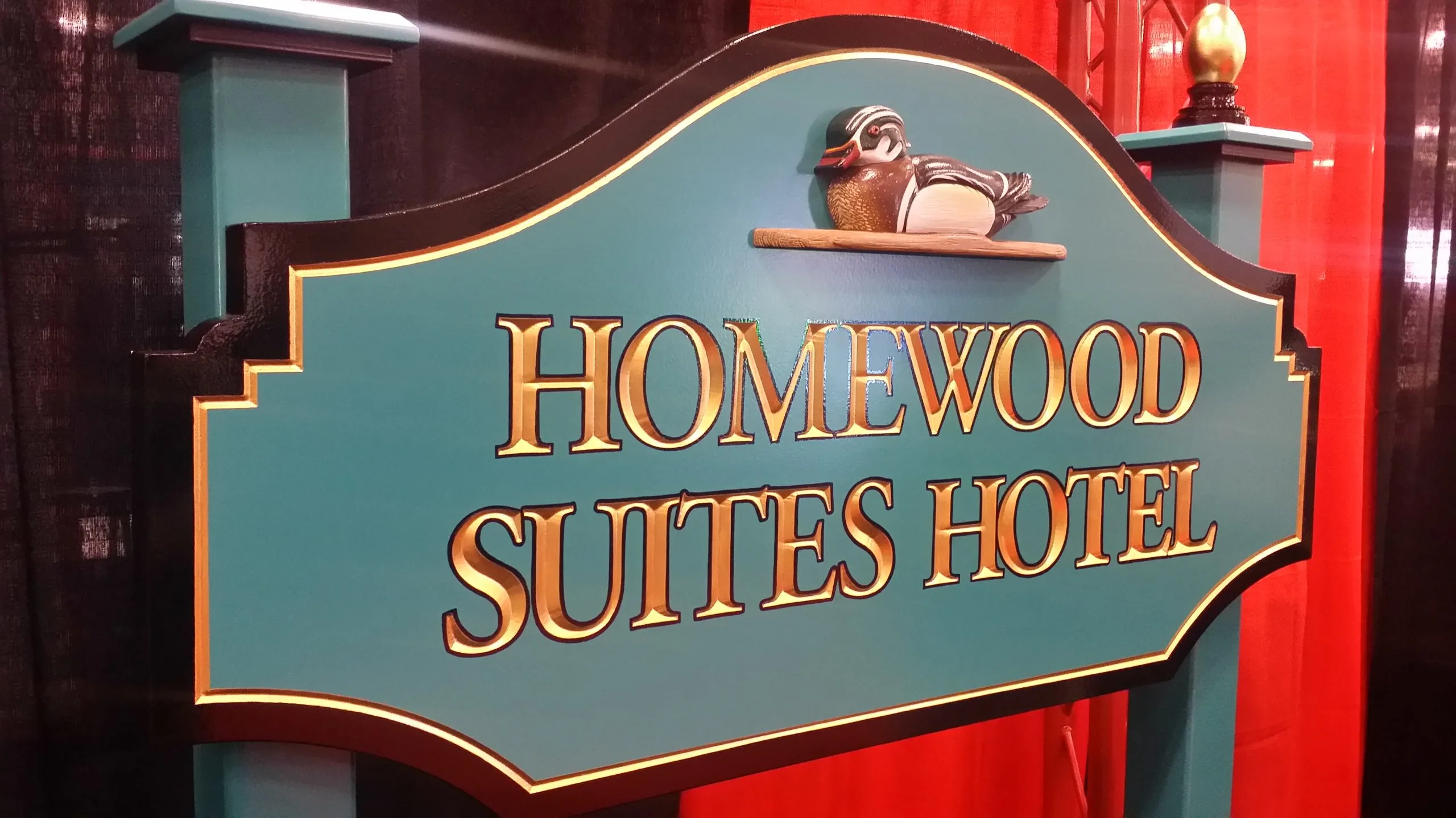 Carved and painted hotel sign with raised gold lettering and a shaped panel