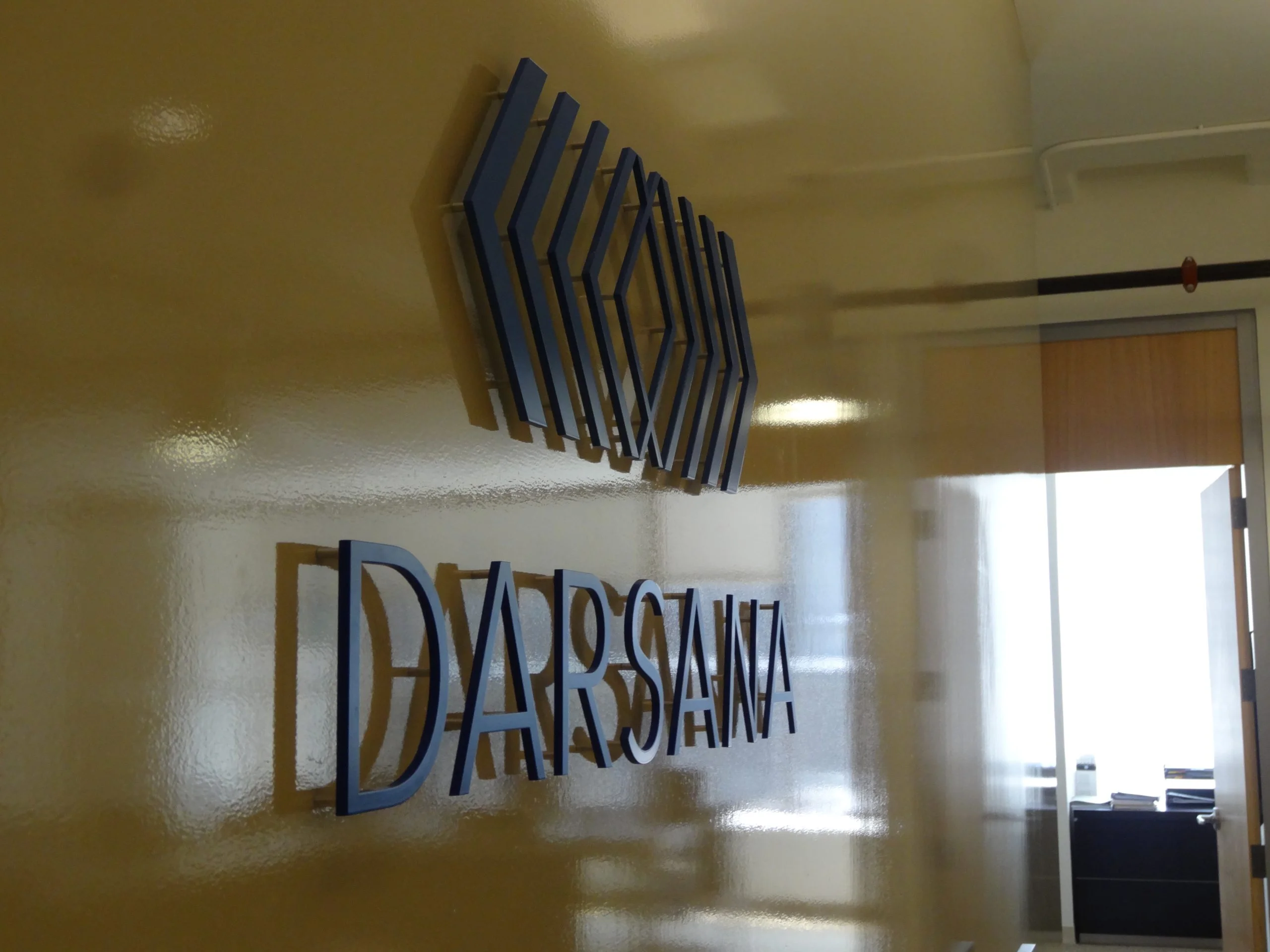 Blue dimensional logo and letters on a glossy office lobby wall