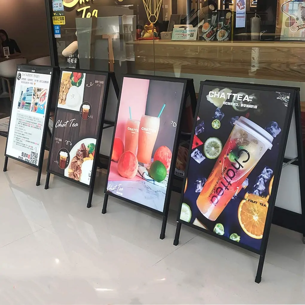 Row of black A frame sidewalk signs with colorful drink and food posters in a shop