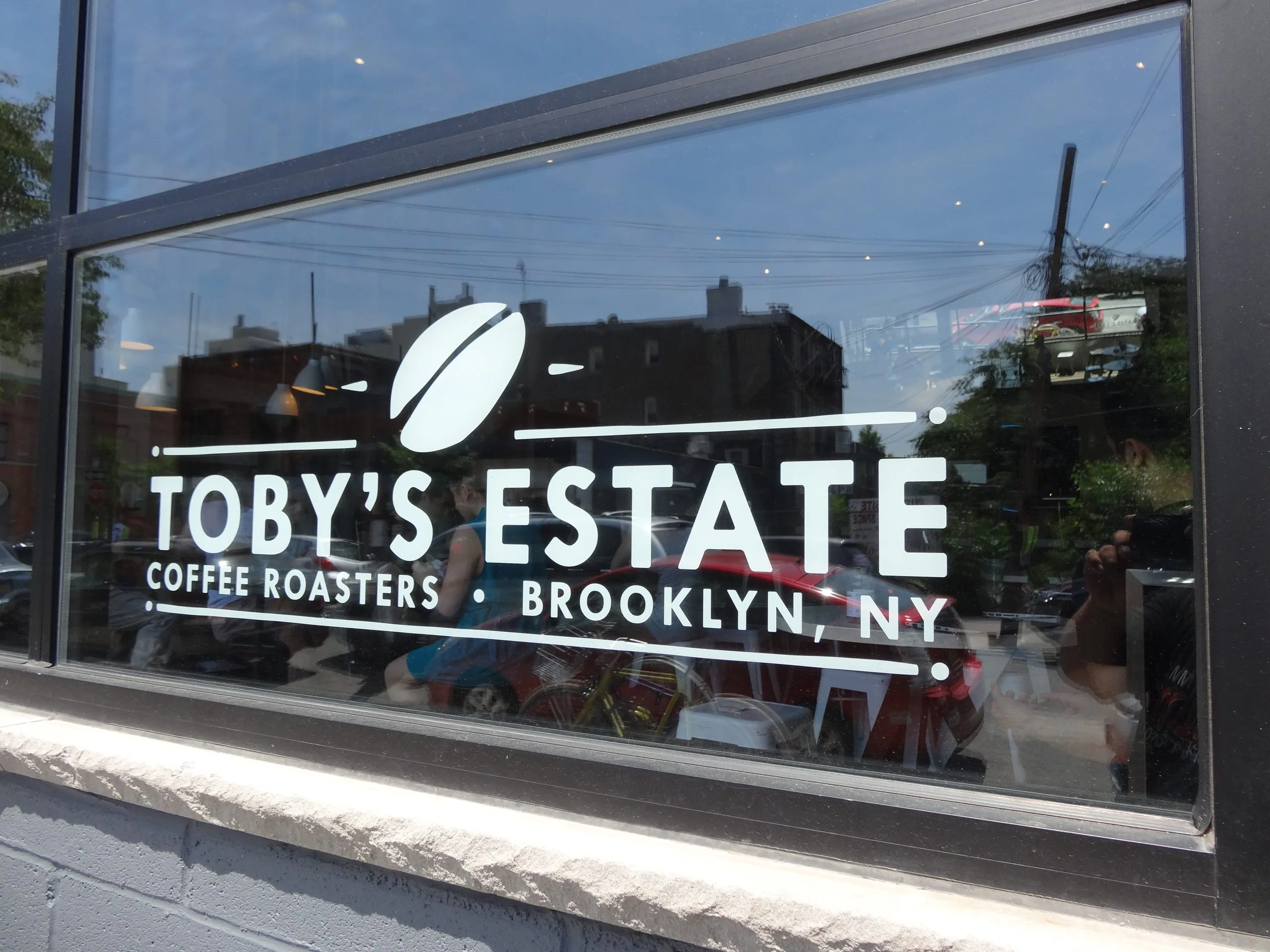 Simple white window lettering for a coffee roaster that leaves the view into the shop clear