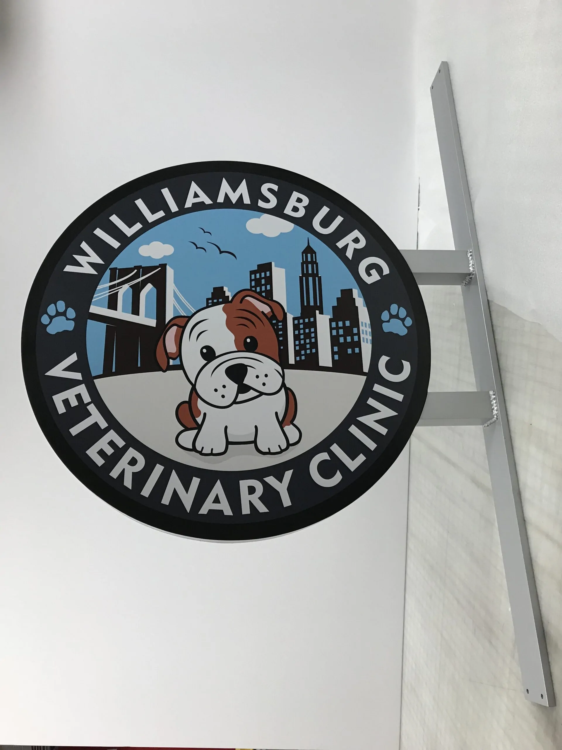 Round projecting sign for a veterinary clinic with bold lettering on a light background