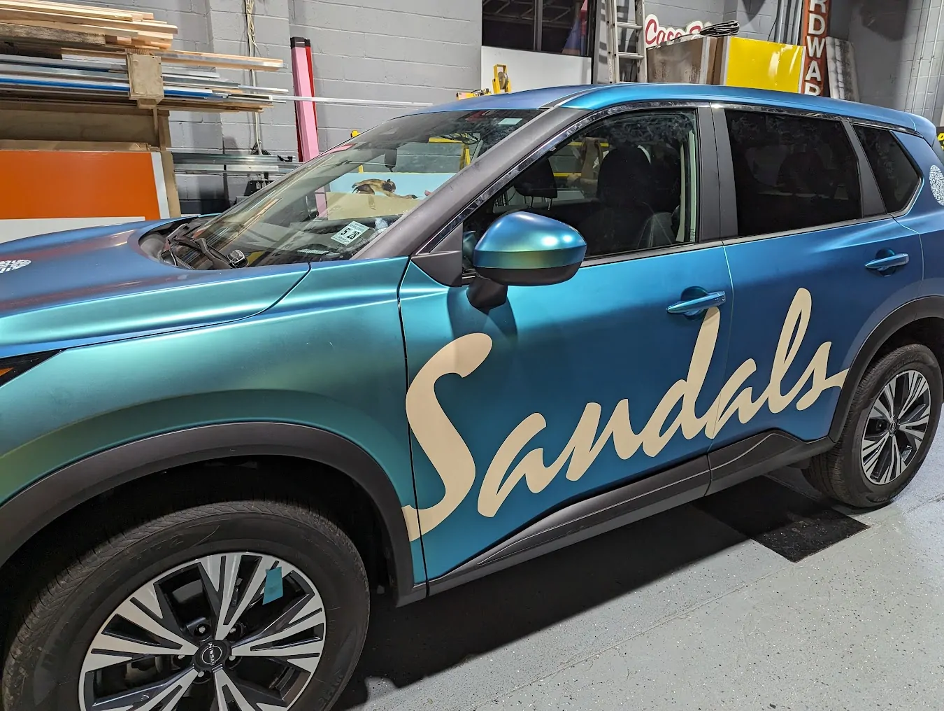 Teal wrapped SUV with large cream script lettering in the Gogi Signs shop