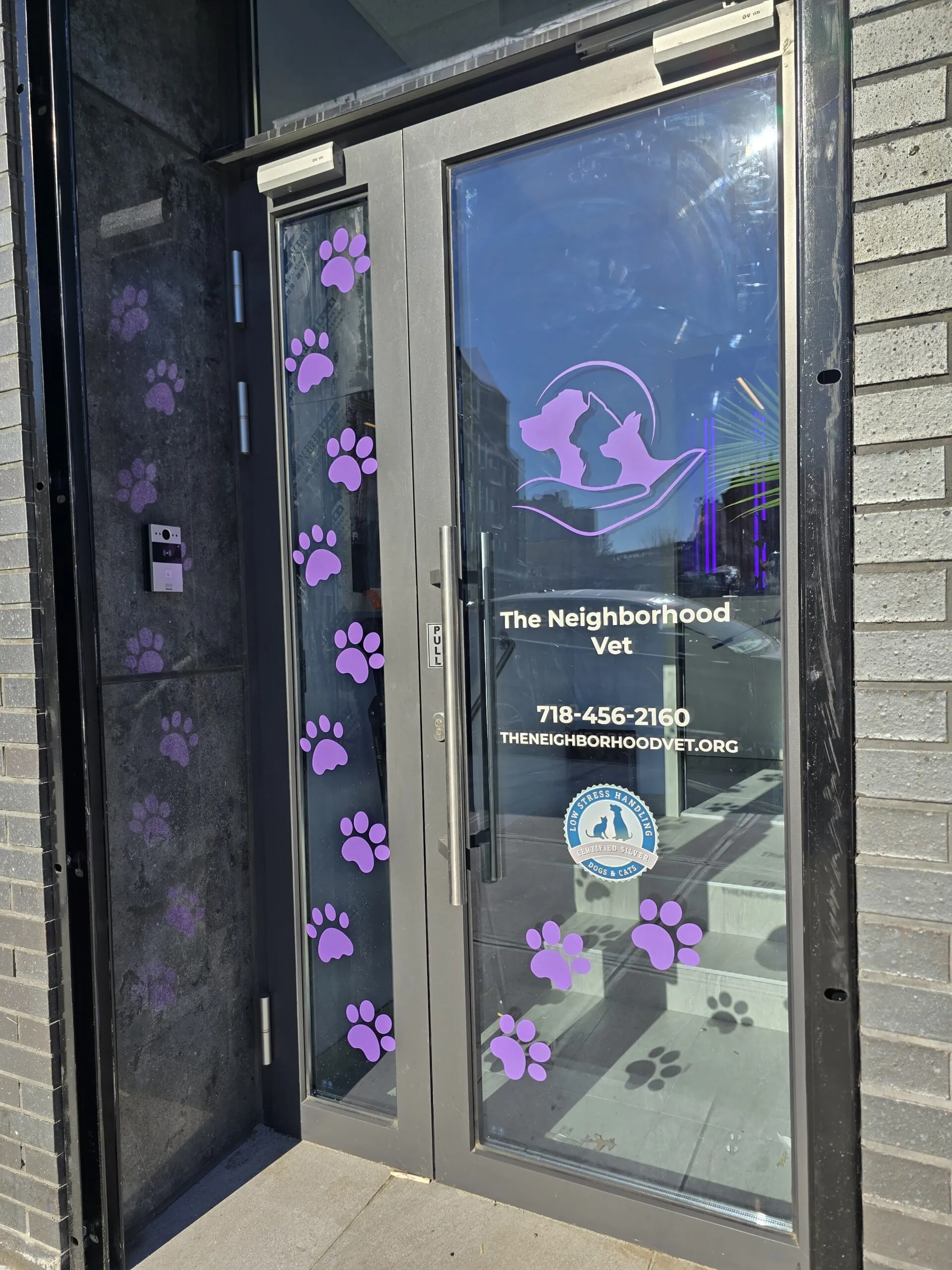Neighborhood vet storefront with paw print door graphics, logo and contact details