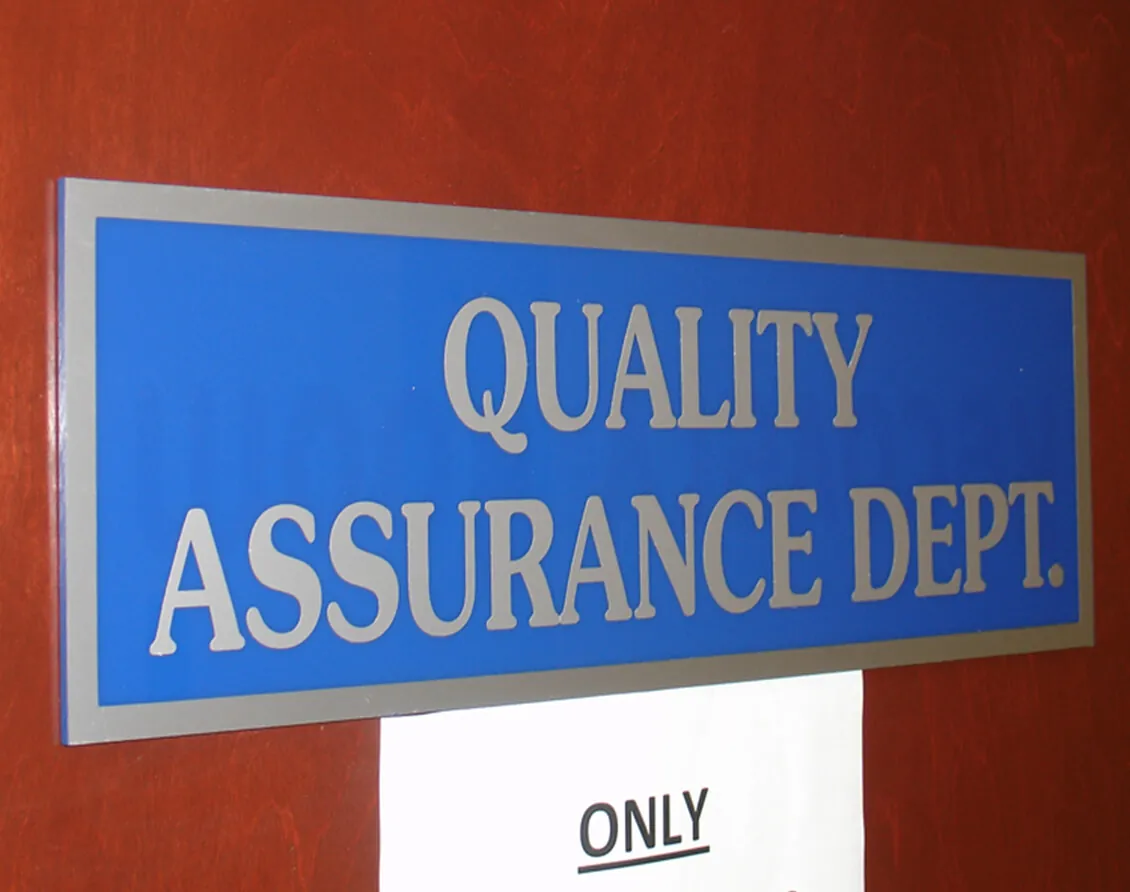 Blue department sign with raised silver lettering mounted on a red office wall
