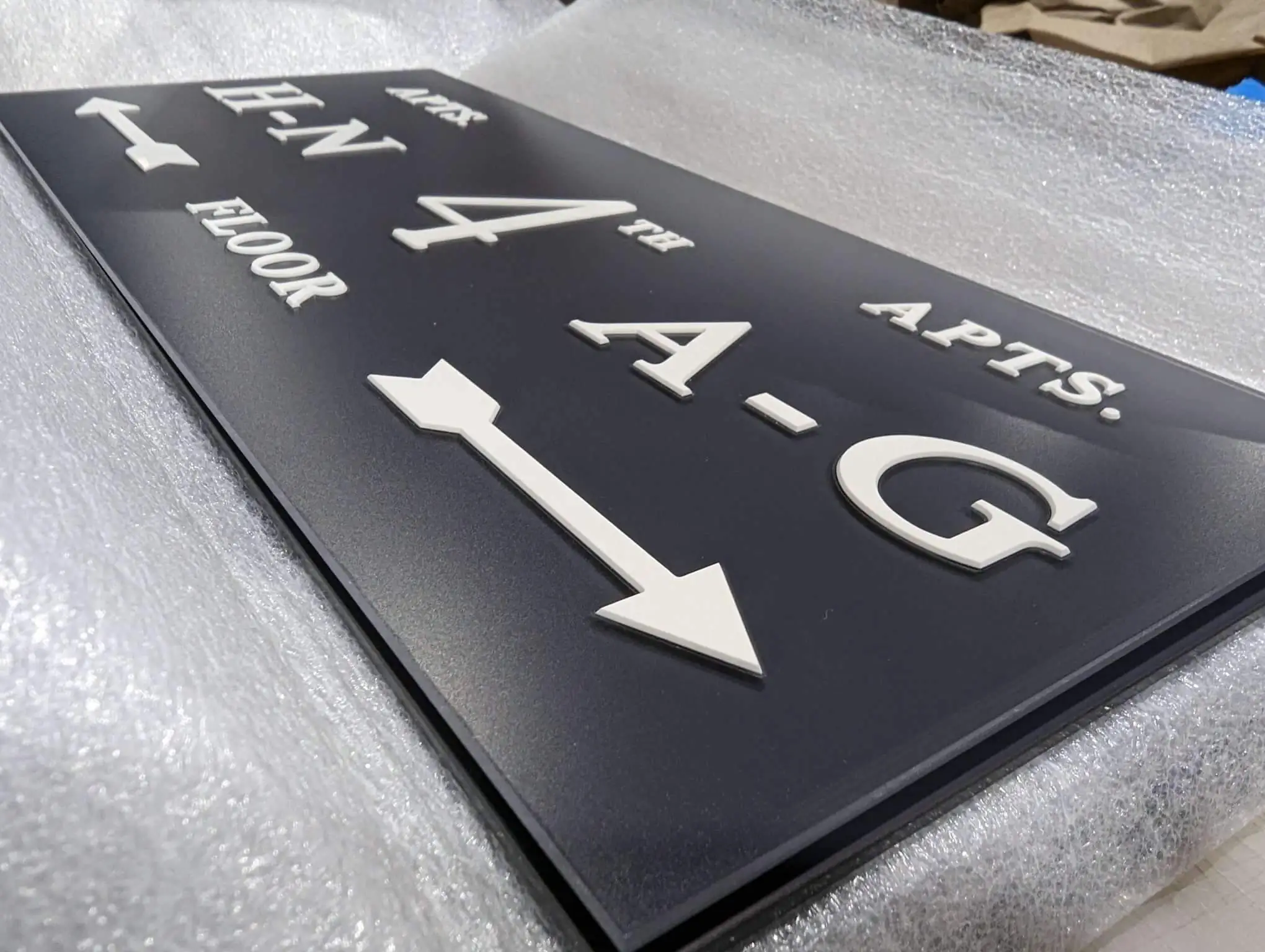Tactile directional sign with raised lettering, braille and an arrow for apartment floors