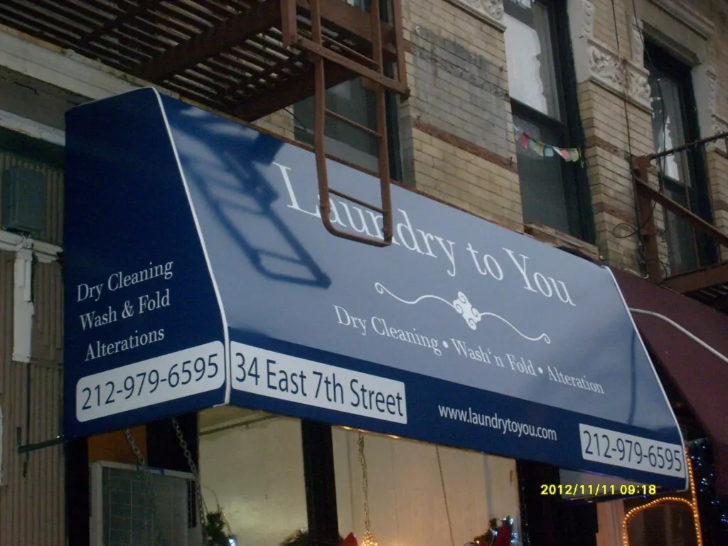 Navy storefront awning with the business name, services and phone number on the valance