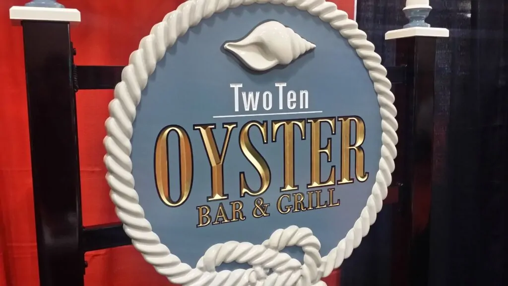 Carved and painted TwoTen Oyster Bar sign with raised gold lettering