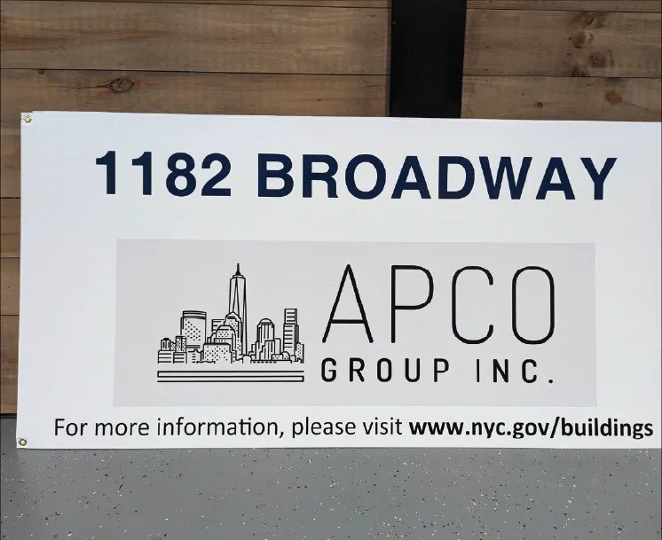 White corrugated plastic construction sign showing a building address and contractor logo