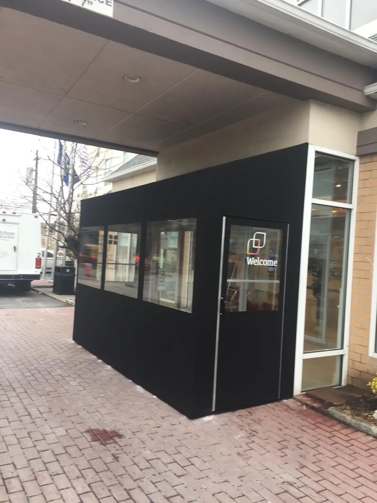Black entrance vestibule with a Welcome decal on the glass door outside a hotel