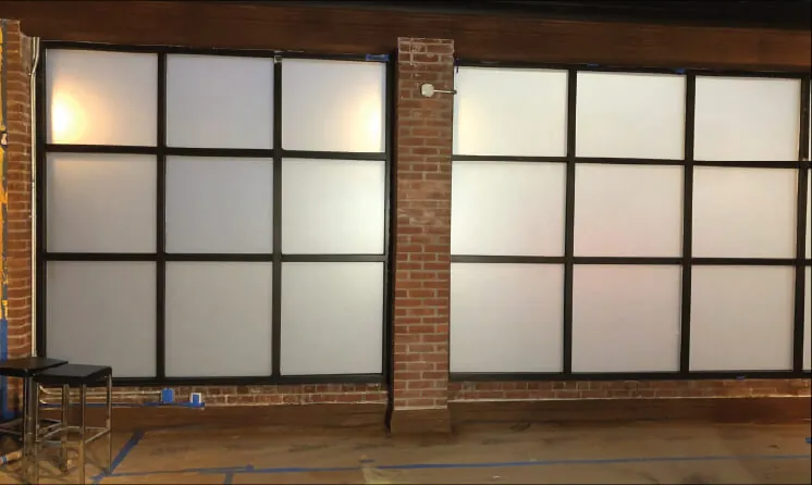 Frosted window film covering the lower and middle panes of a brick walled office