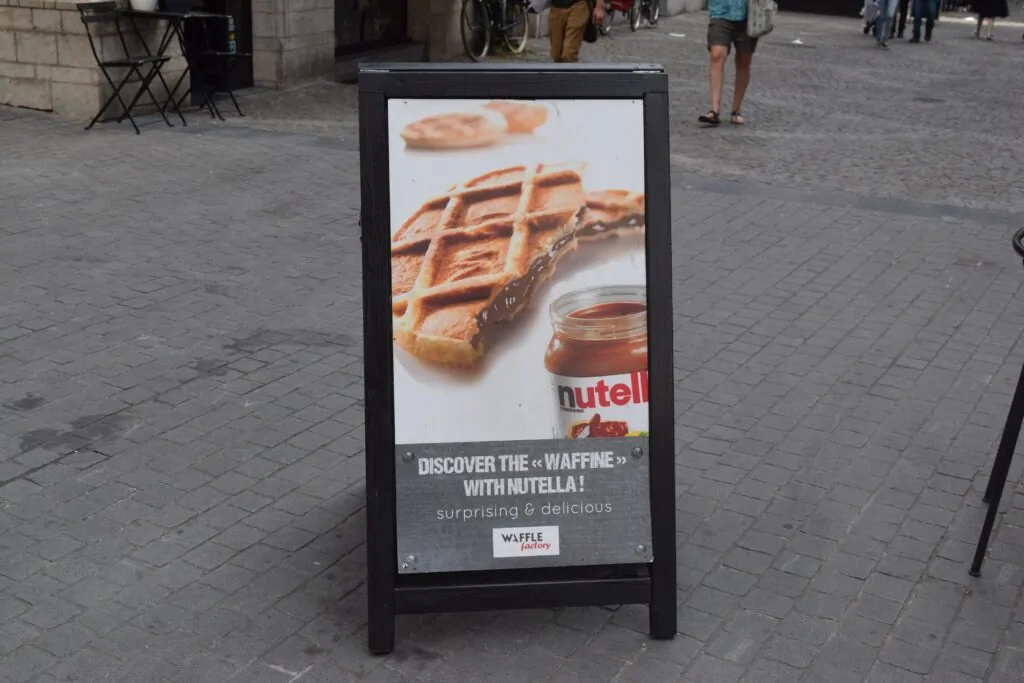 A-frame sidewalk sign with a promotional poster placed on a city sidewalk