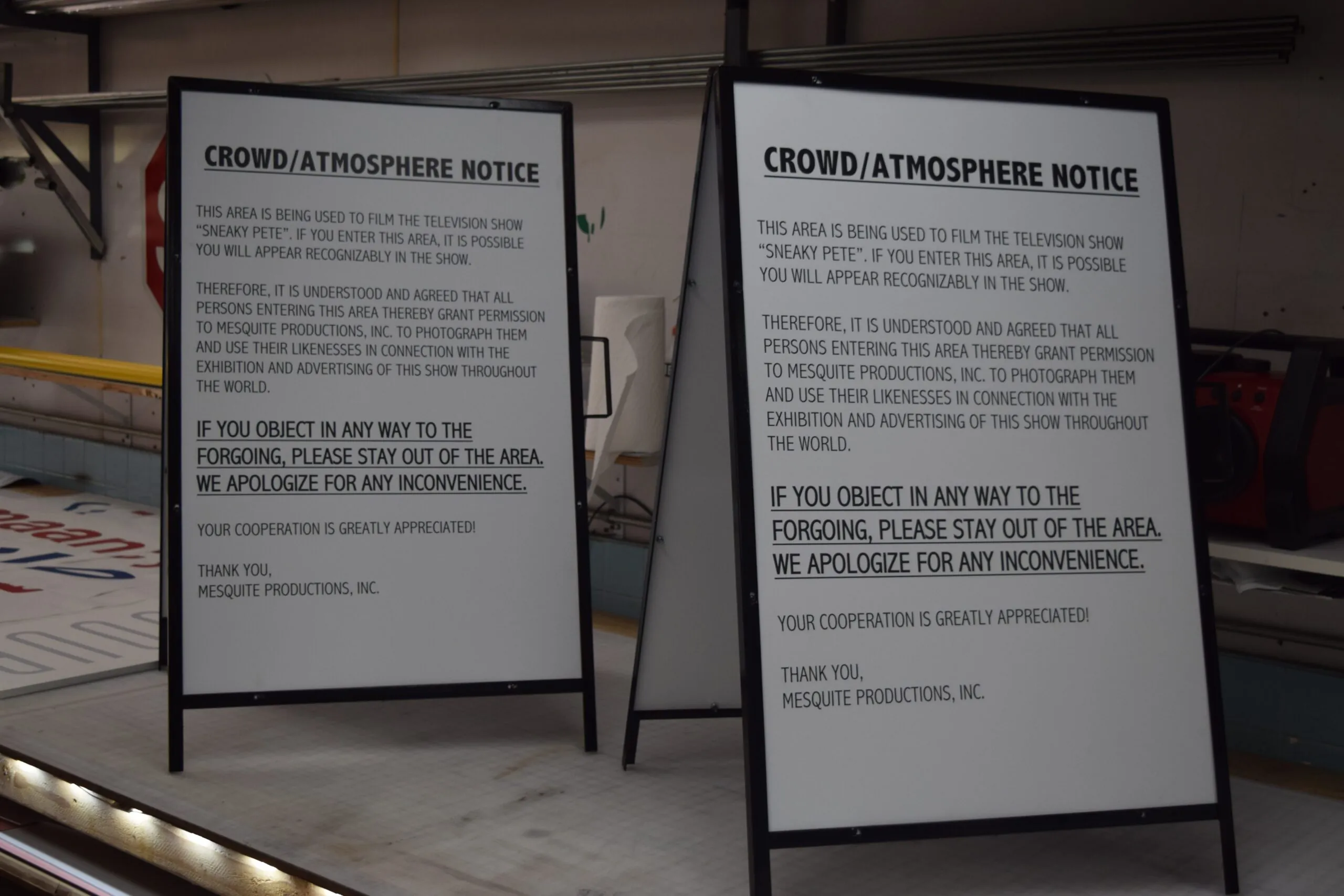 Two black framed A frame sidewalk signs with printed notices in a sign shop