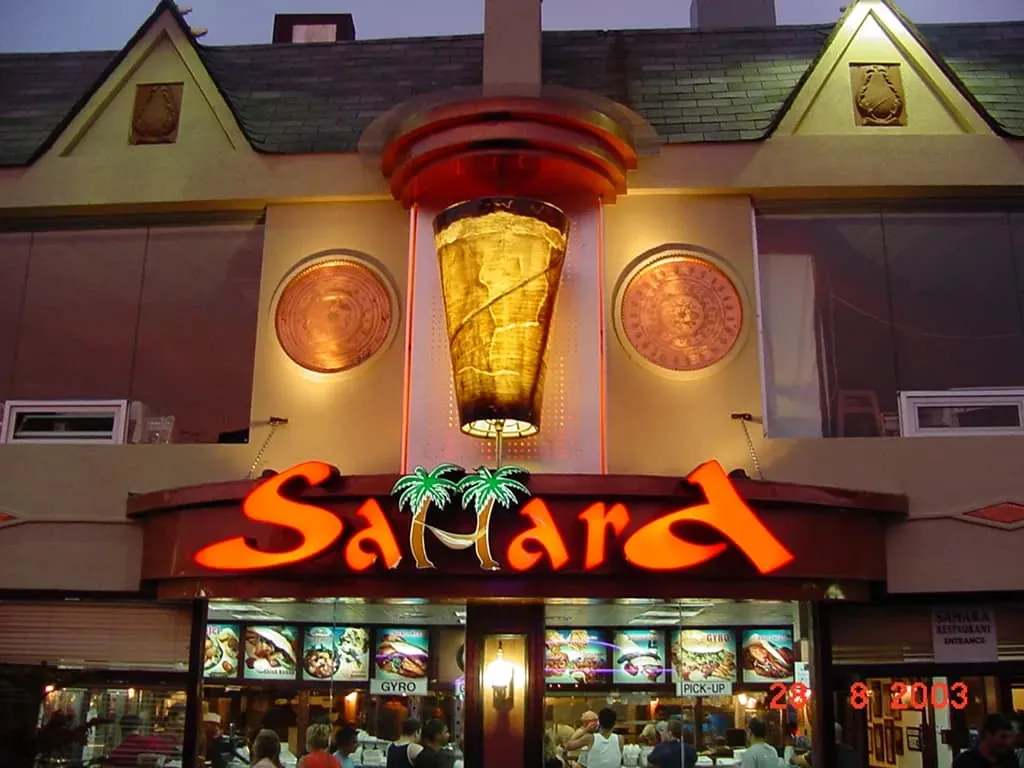 Corner storefront with a lit sign and lit window graphics at night