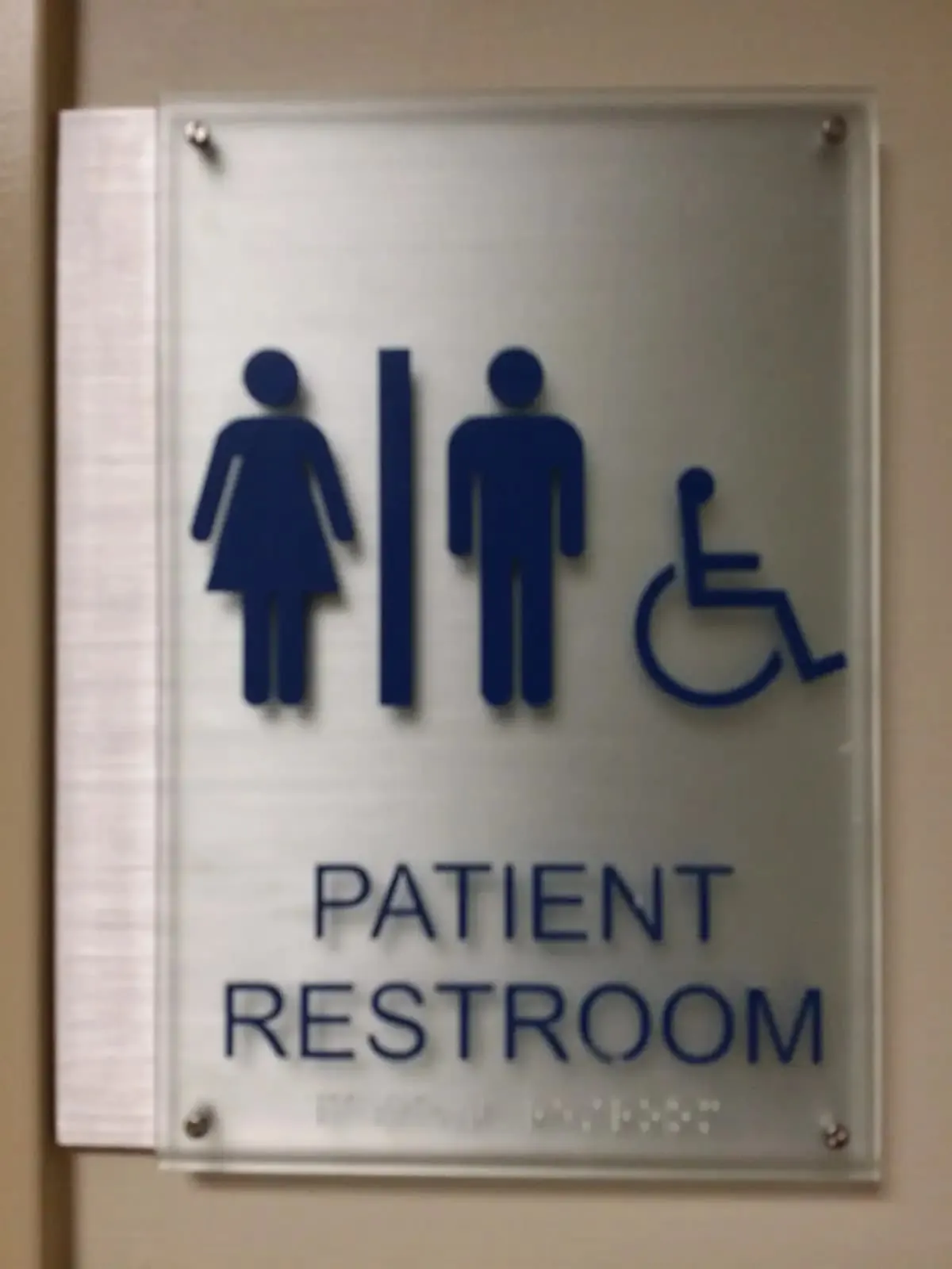Patient restroom sign with blue pictograms on a frosted acrylic panel