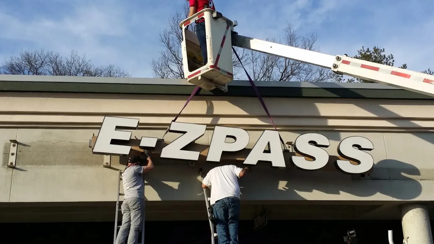 Technician on a lift servicing a large illuminated sign