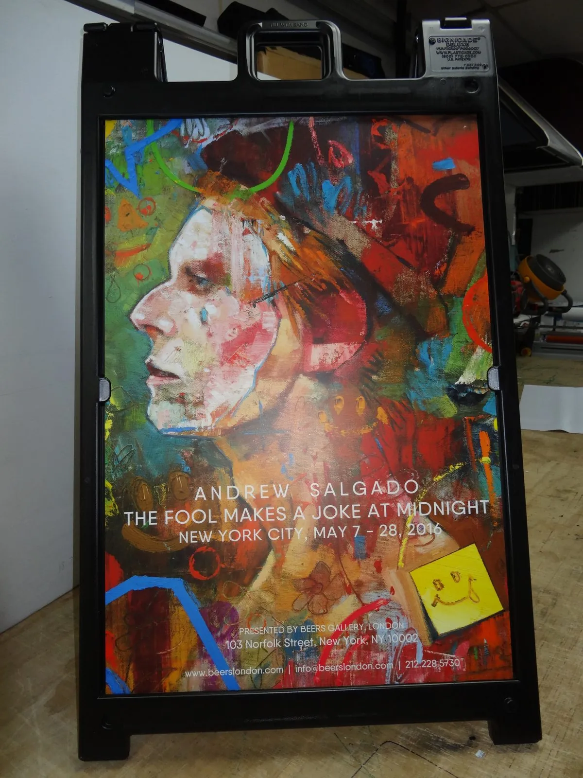 Black A frame with a full color painting on a poster for an art show