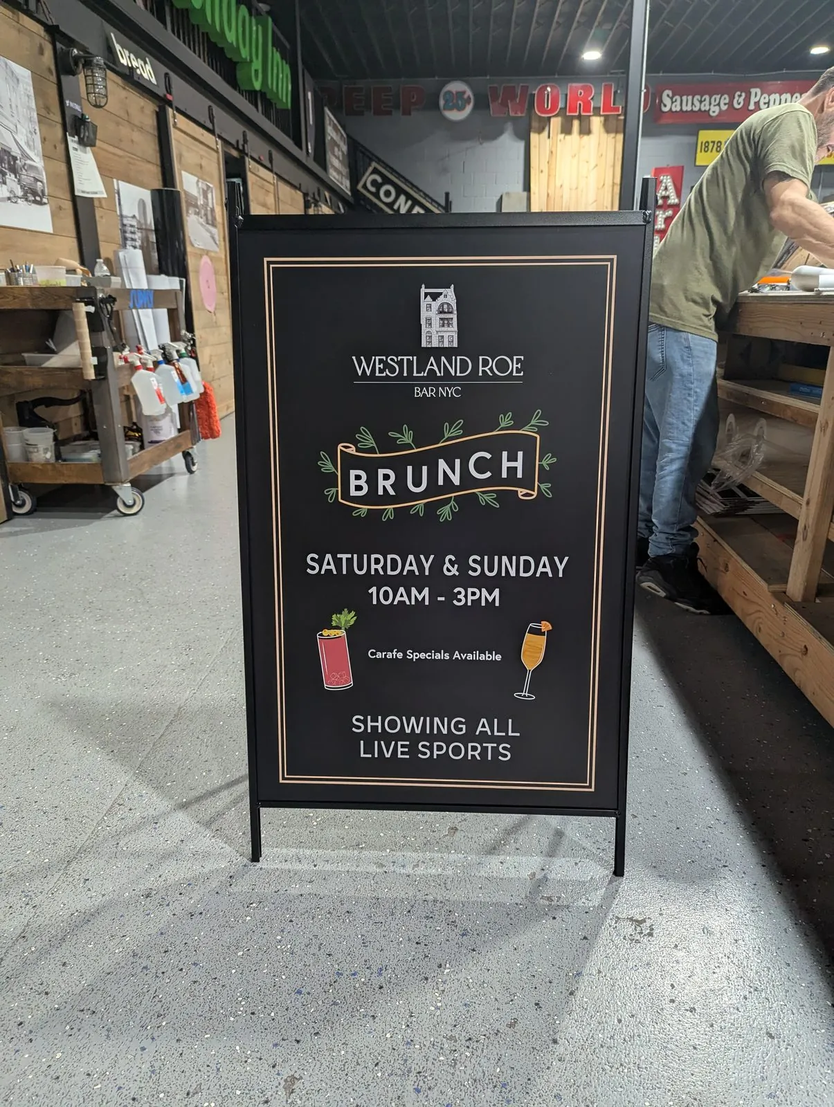 Black A frame face listing weekend brunch hours in white and gold
