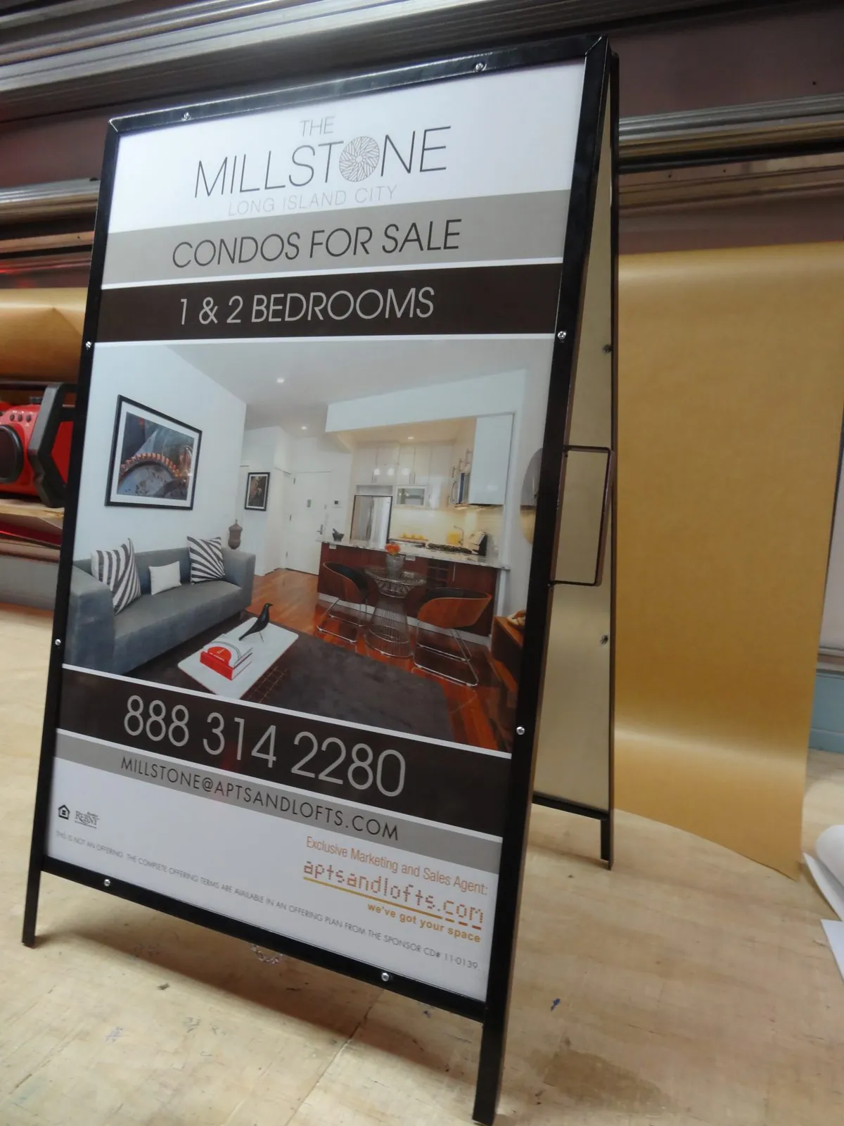 A frame sign with a condo listing photo and a phone number