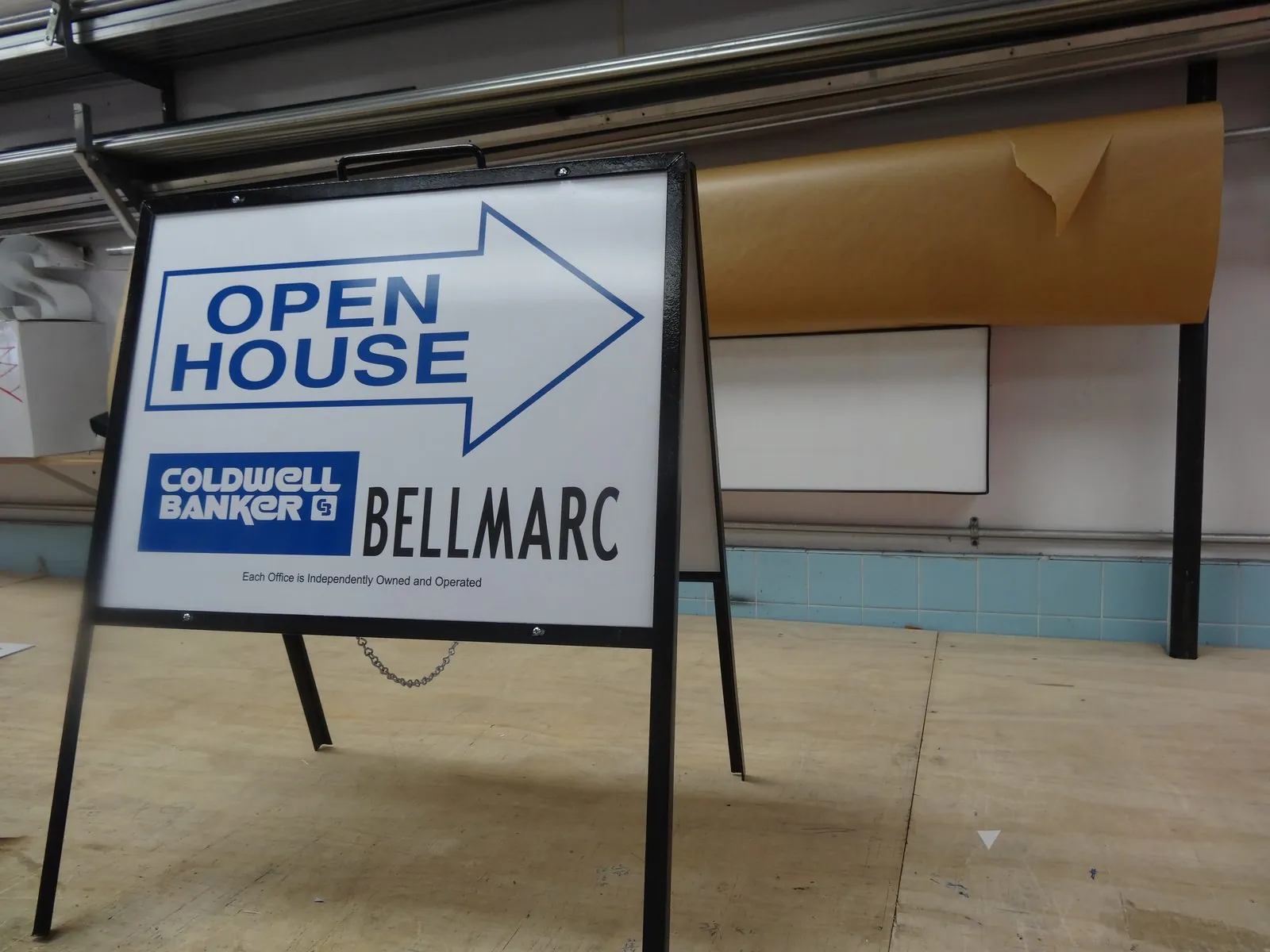 A frame sign with a blue Open House arrow and a realty logo