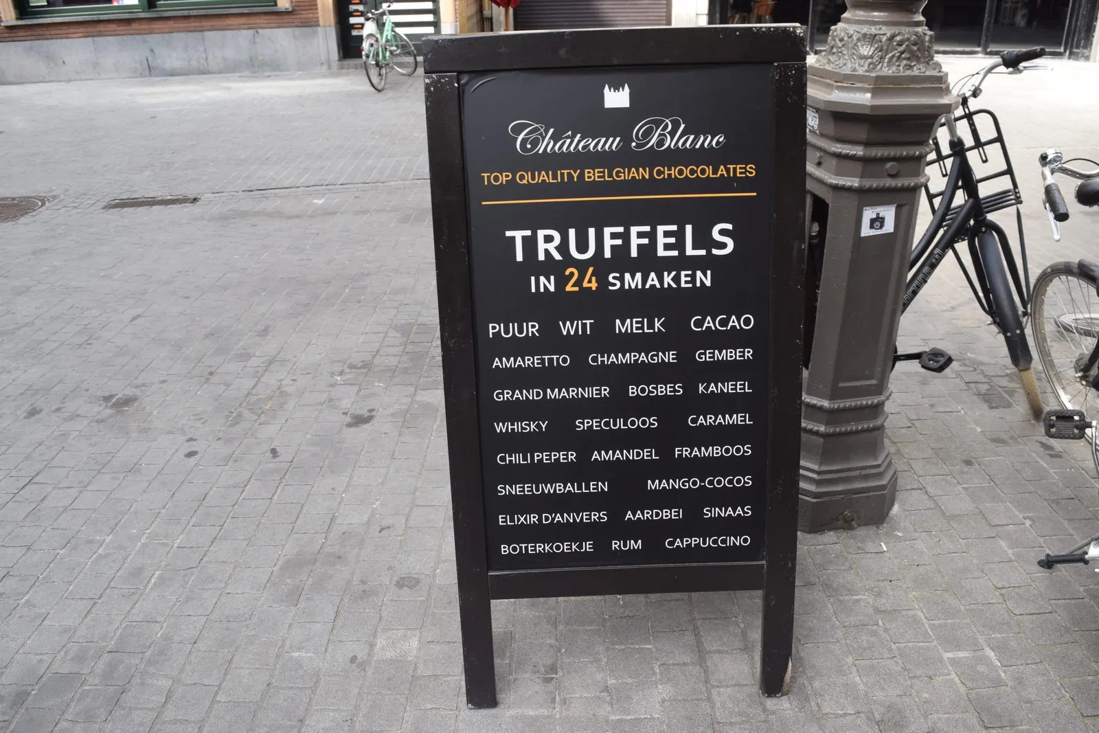 Black A frame sign with a printed chocolate truffle menu on a brick sidewalk