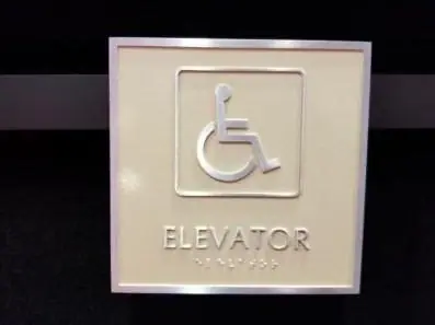 Cream ADA elevator sign with the accessible symbol