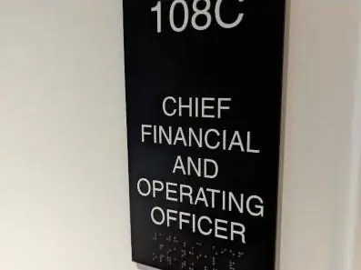Black ADA office title sign with raised letters and braille