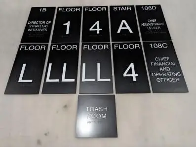 Set of black ADA signs laid out in the shop