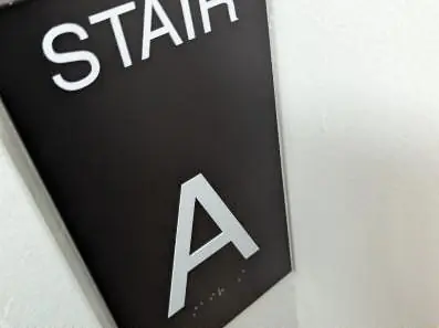 Black ADA stair sign installed by a door