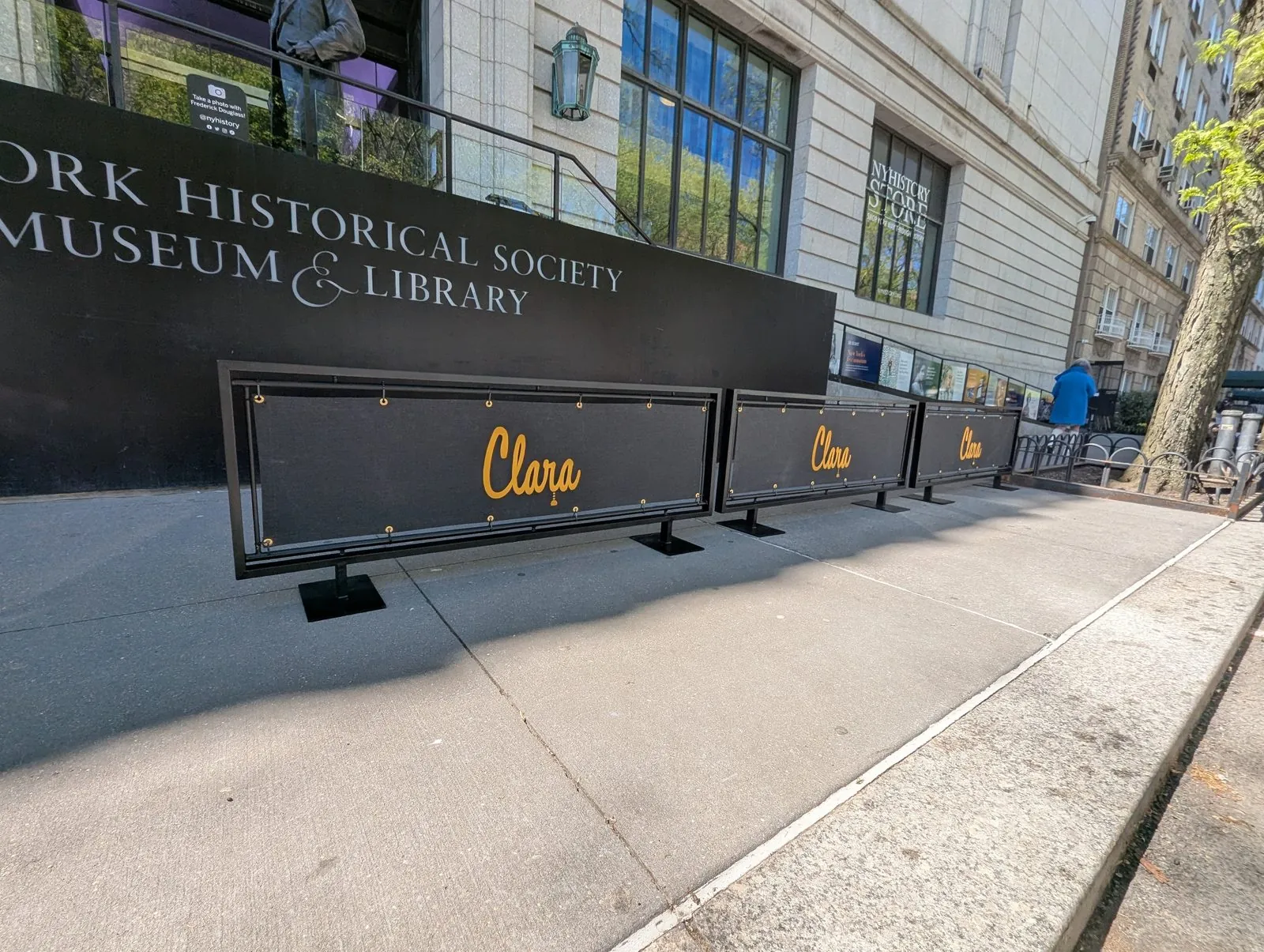Black cafe barriers with gold script lettering along a building front