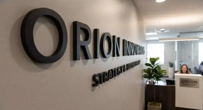 Black dimensional letters for Orion on a white office wall above a reception area