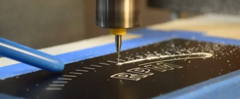 CNC router engraving a logo into a black sign panel at the Gogi Signs shop in Linden, NJ