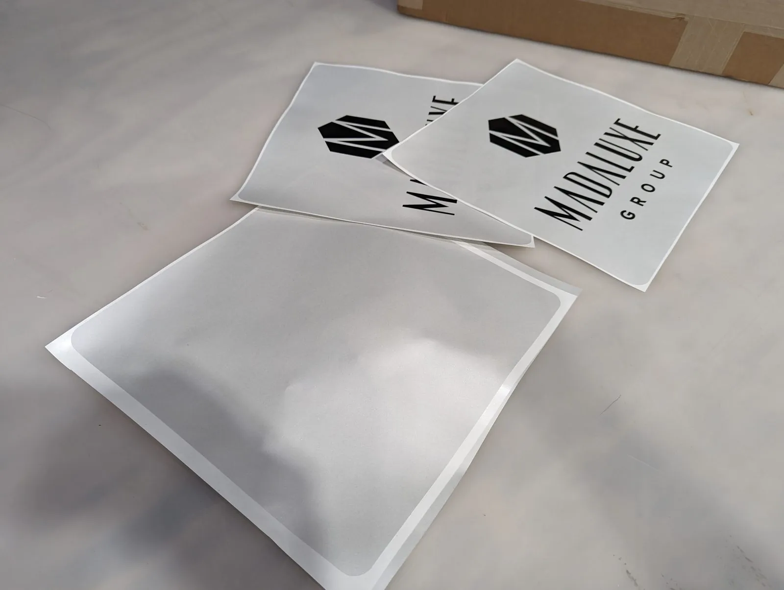 Three cut vinyl logo sheets on a table, one covered with clear transfer tape