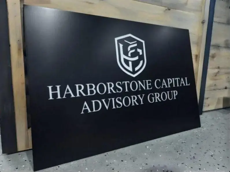 Black Dibond sign panel with a silver crest for Harborstone Capital before installation