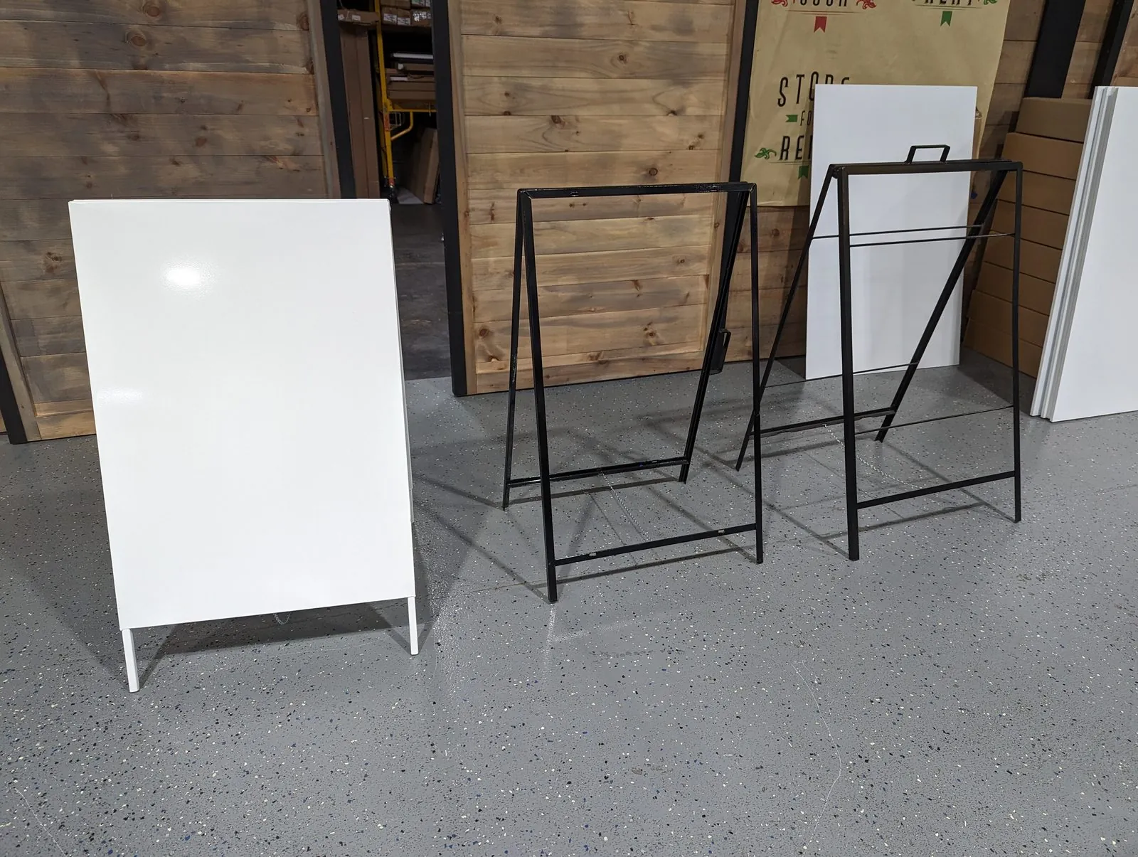 Empty white and black A frame sidewalk sign frames in the shop, ready for printed faces
