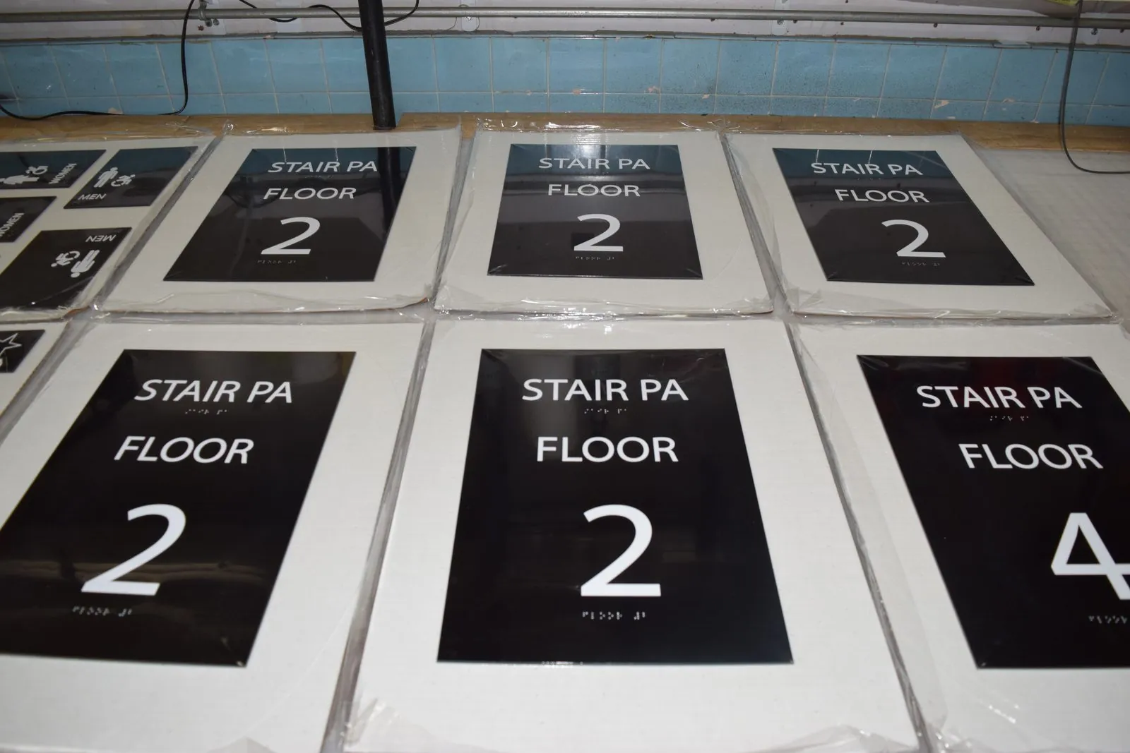 Rows of finished Stair PA Floor 2 signs on protective backing in the shop