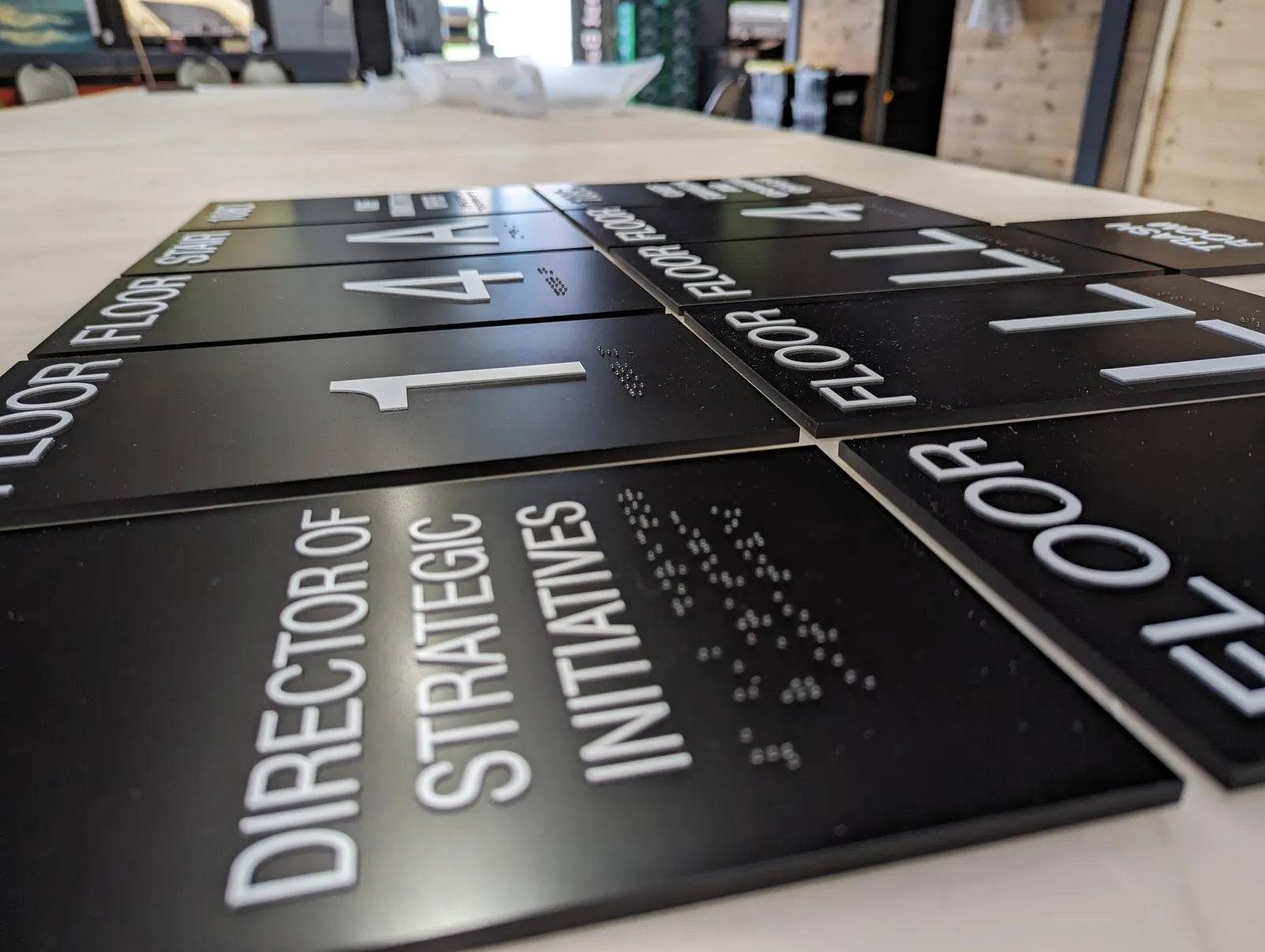 Black floor number and room signs with raised white characters and braille laid out as one set in the shop