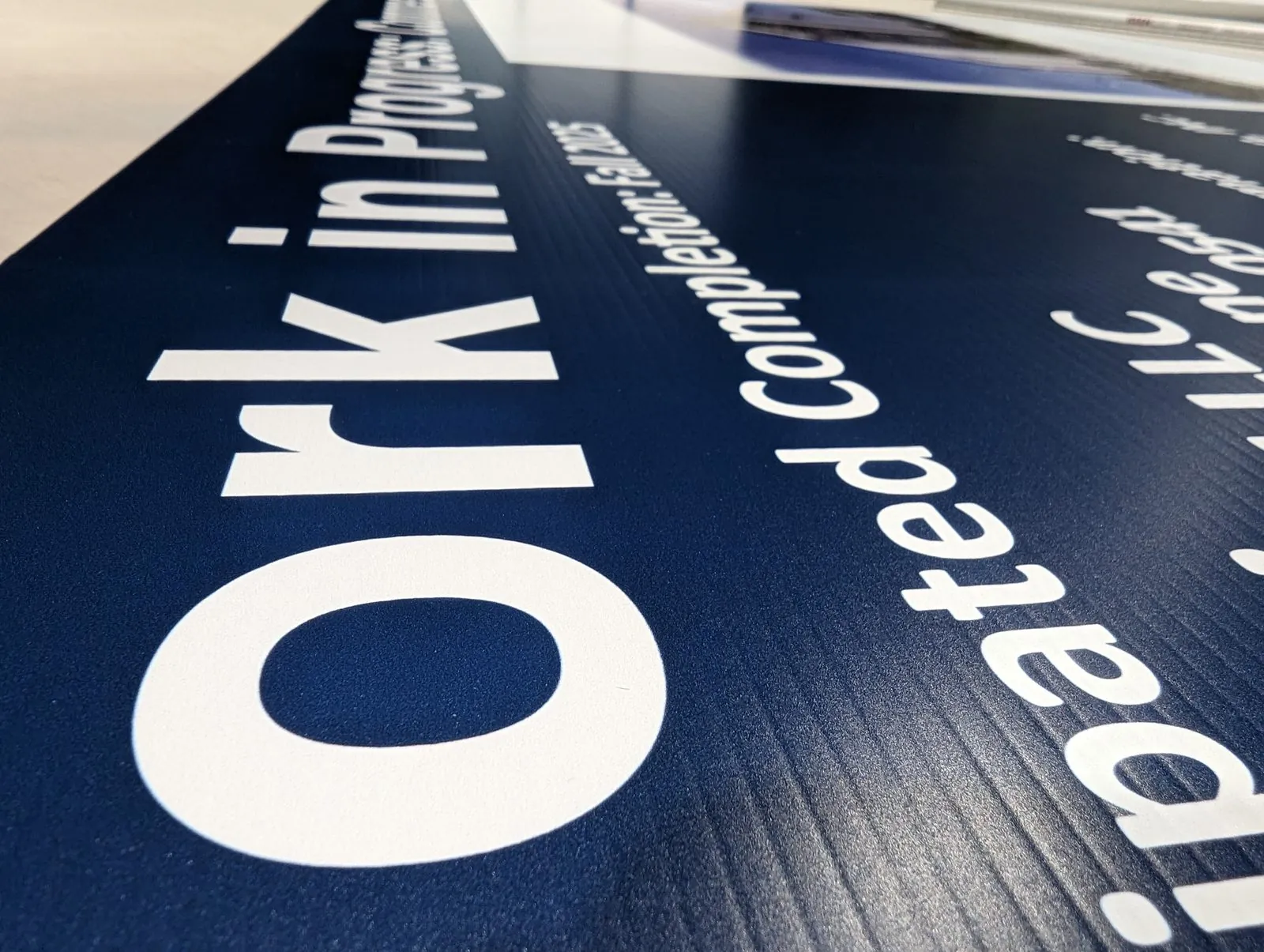 Close up of a navy Work in Progress board printed on fluted coroplast