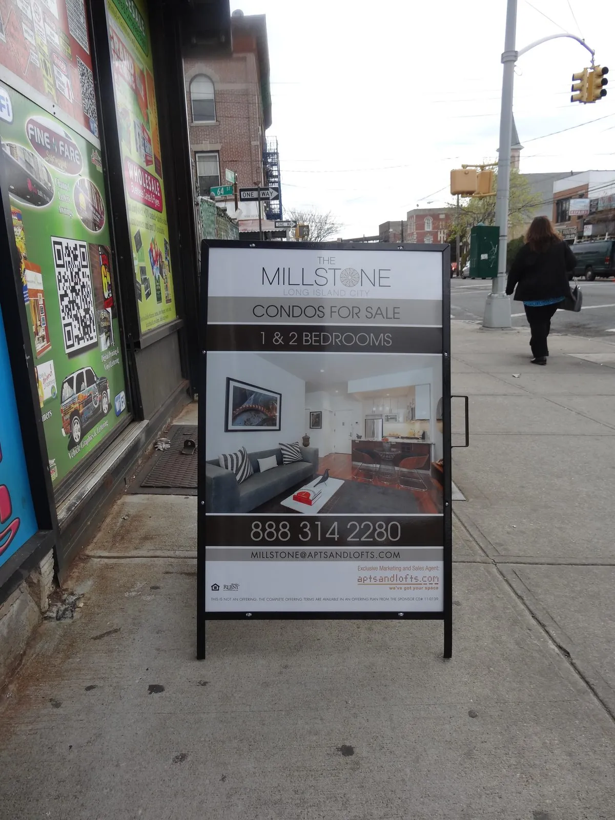Metal A frame condo sales sign on a city sidewalk outside a storefront
