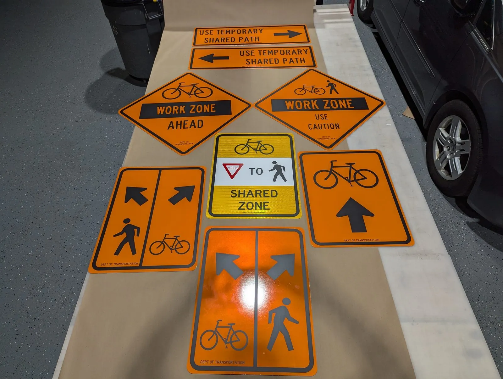 Set of orange work zone and bike lane signs laid out on the shop floor