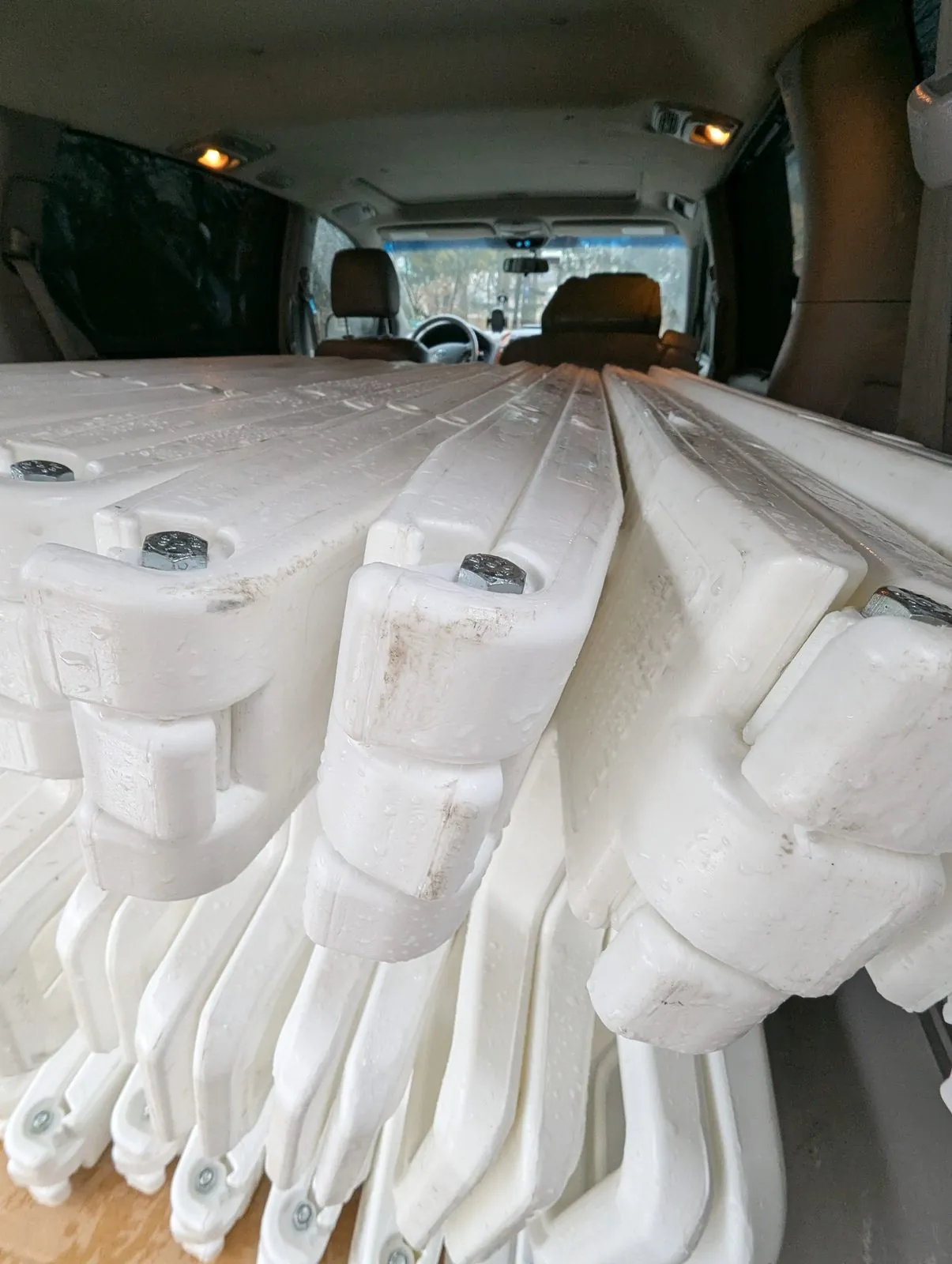 Stack of white plastic sandwich board frames loaded in a van