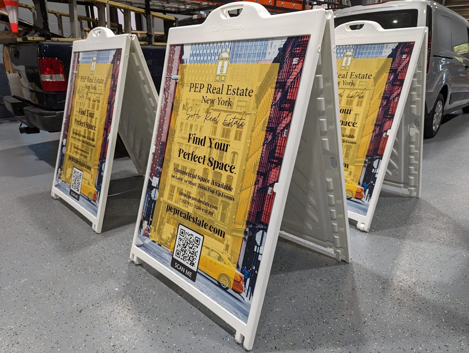 White plastic sandwich boards with yellow real estate posters fitted in the shop