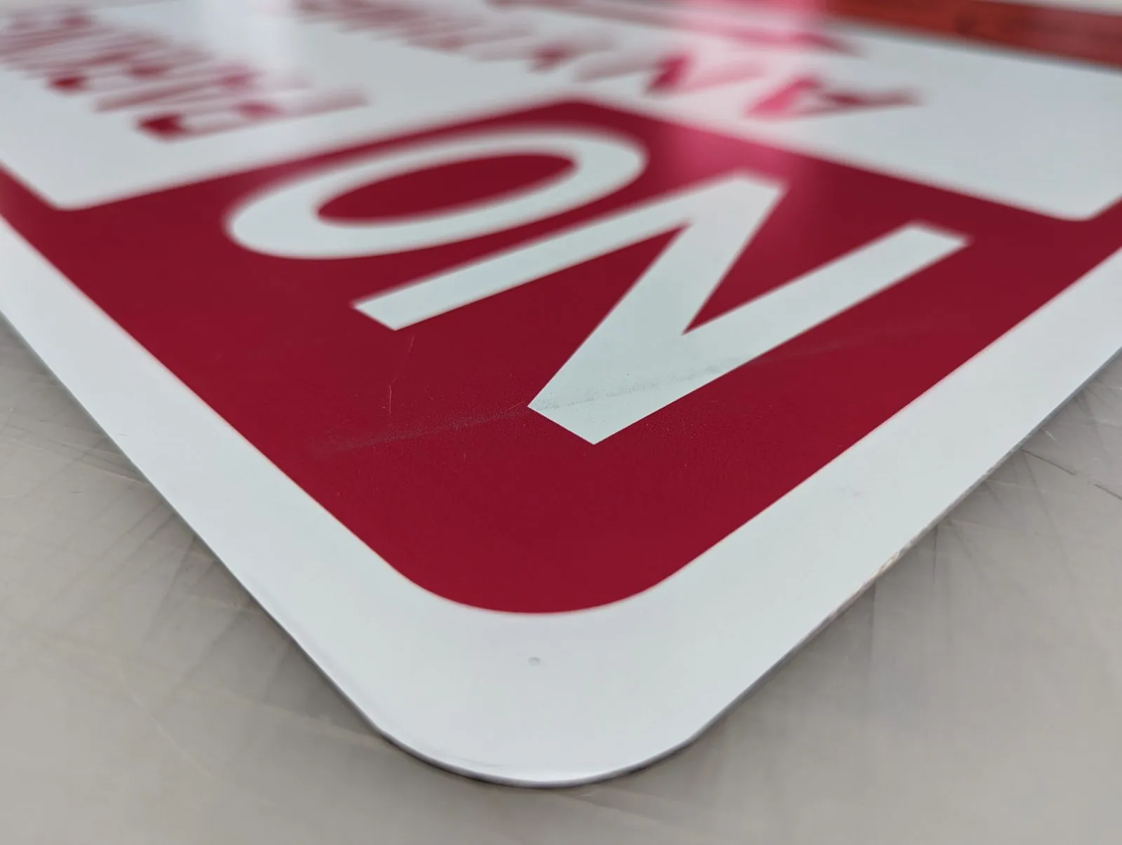Rounded corner of a printed aluminum No Parking sign on a shop table