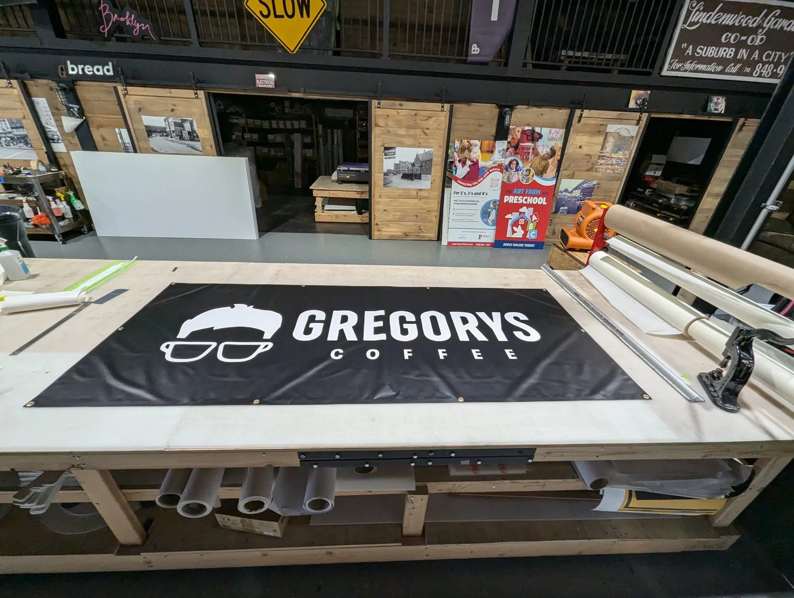 Black banner with a white logo laid flat on the shop table for finishing