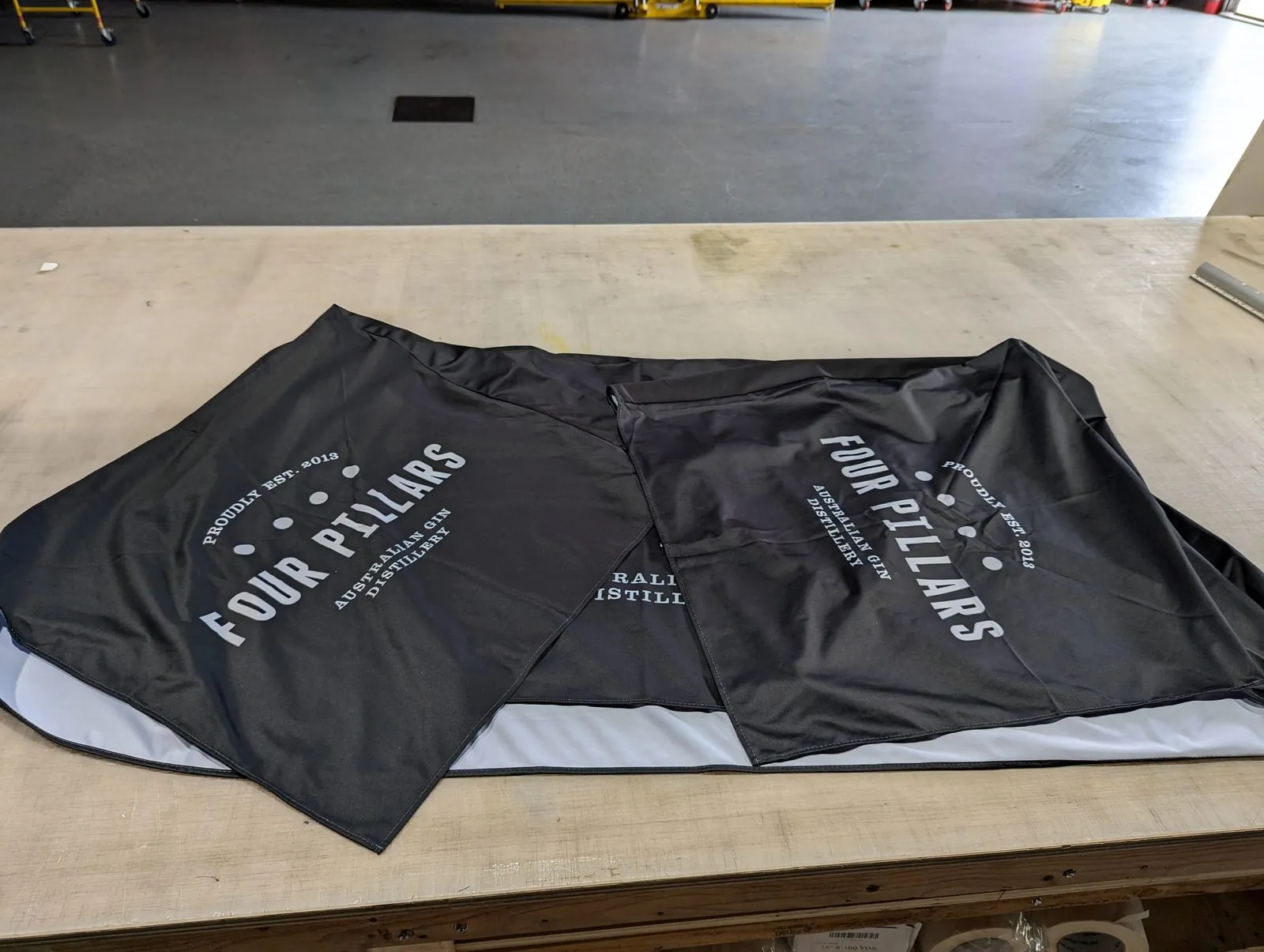 Printed black fabric pieces with a white distillery logo laid out on our shop table