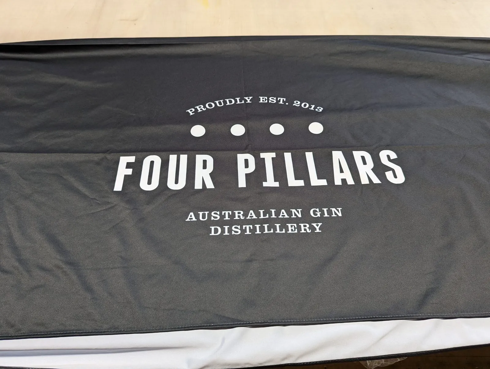 Black printed fabric with a white logo laid flat on our shop table