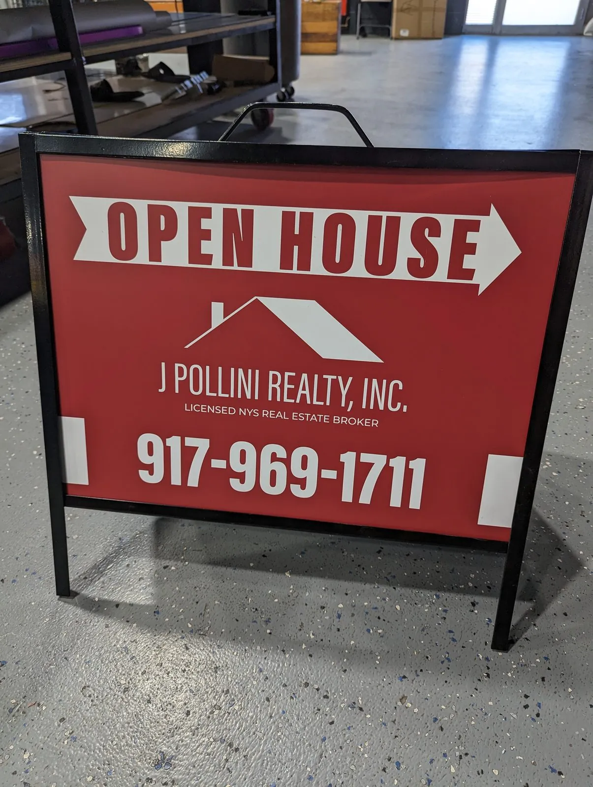 Red metal A frame sign reading Open House with an arrow, a realty name and a phone number