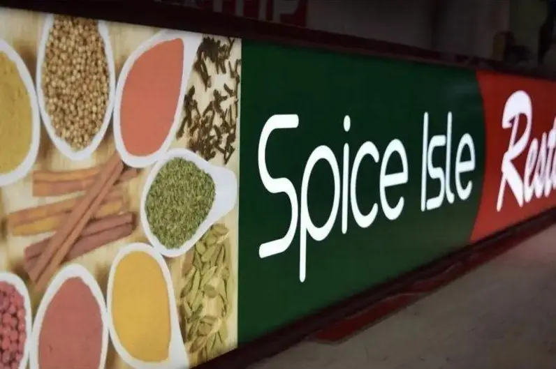 Colorful restaurant sign with spice bowl graphics above a dining room