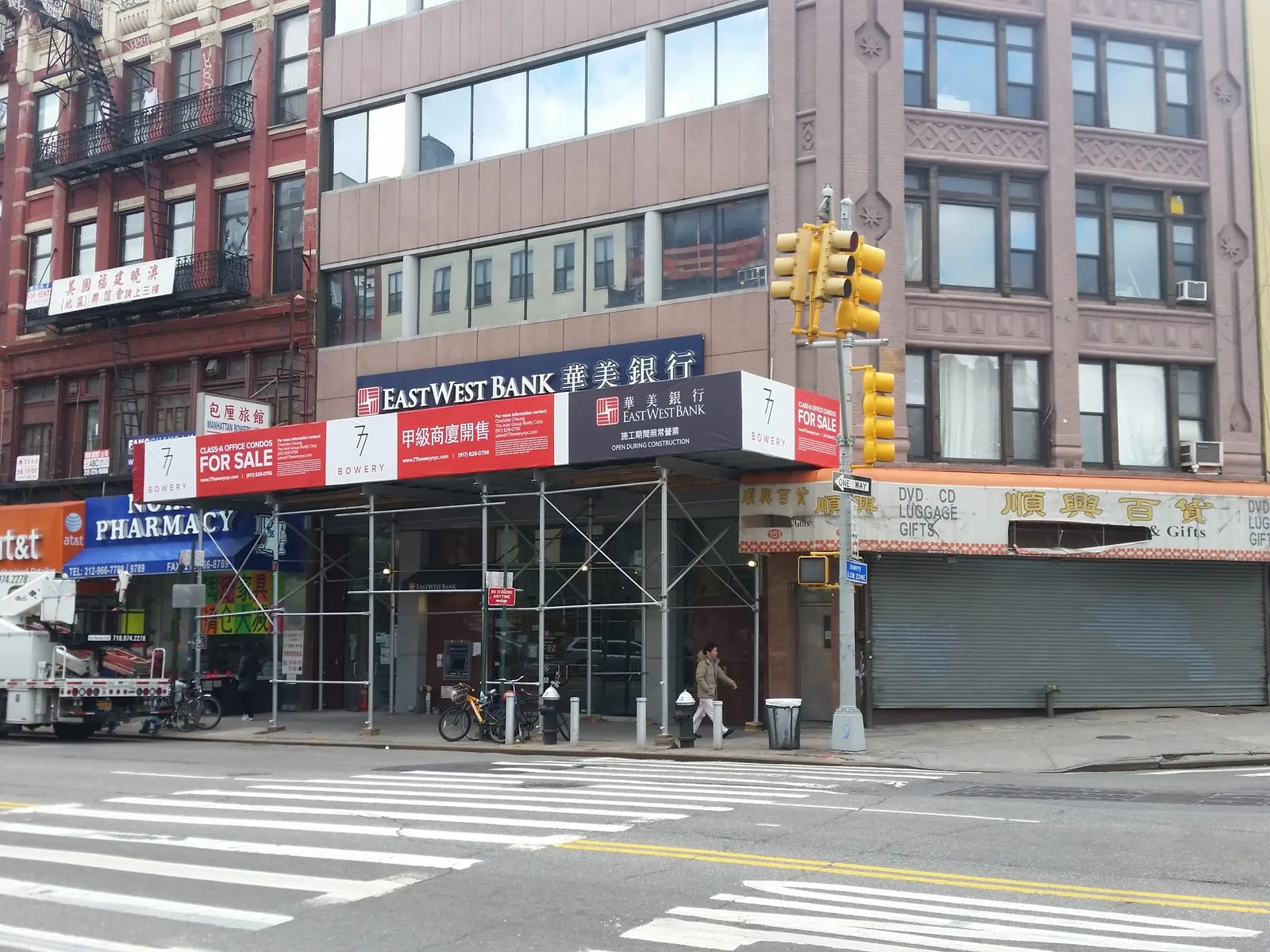Printed banners along a sidewalk shed wrapping the corner of a city building