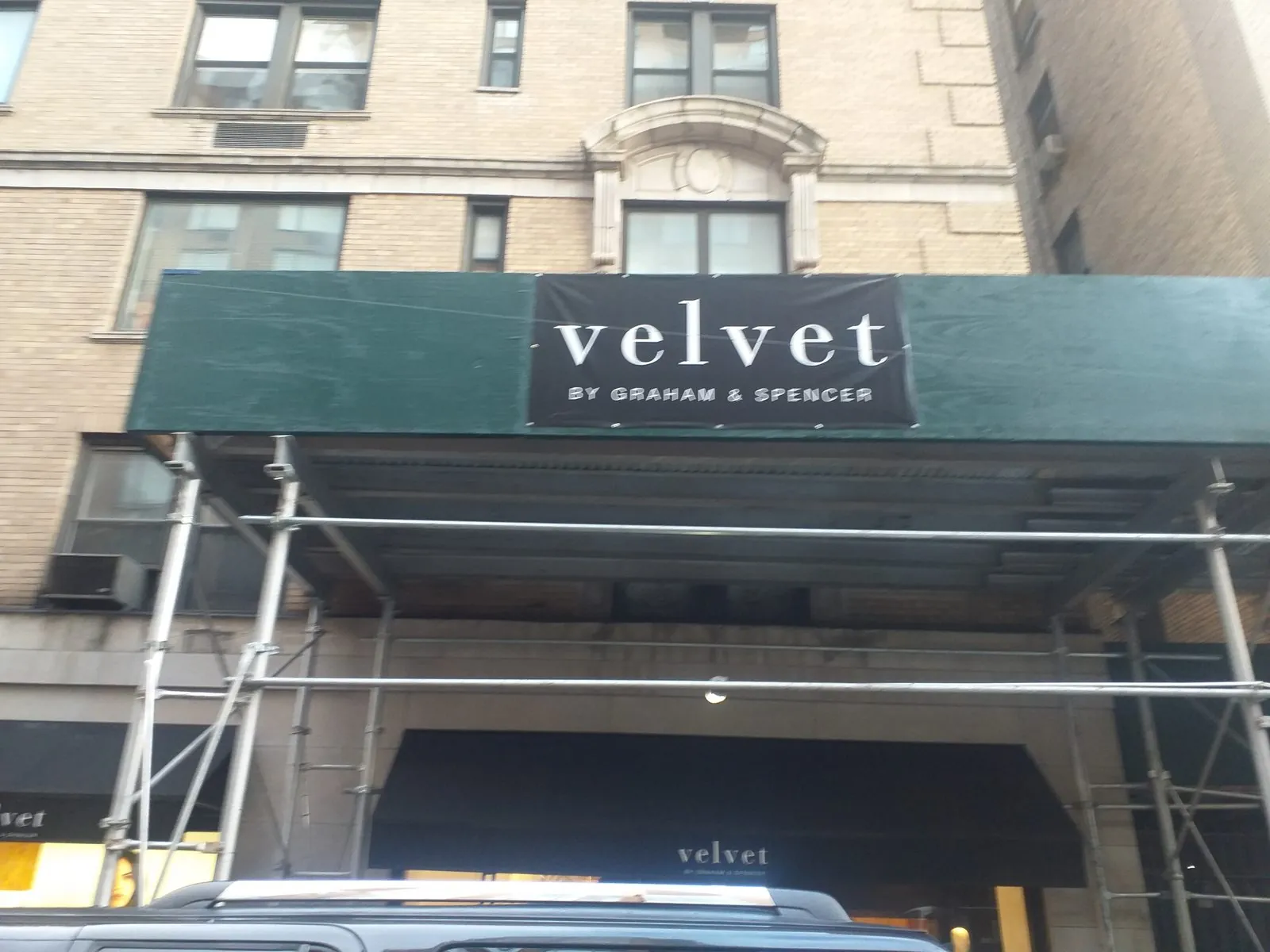 Dark green sidewalk shed with a black and white name banner on the front
